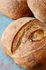 Fresh homemade bread on a gray-blue background, with flax seeds on whole wheat flour. French bread round shape. Bread baking. Unleavened bread