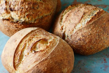 Fresh homemade bread on a gray-blue background, with flax seeds on whole wheat flour. French bread round shape. Bread baking. Unleavened bread
