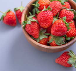 A bowl of beautiful and delicious strawberries isolated on a blue background, closeup, topview, copyspace.