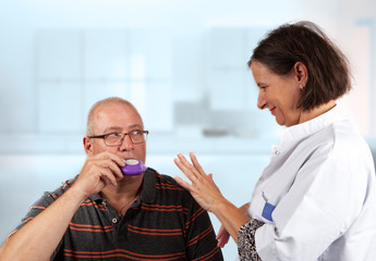 nurse explains an inhaler to a patiënt: hold breath for 5 seconds - obrazy, fototapety, plakaty