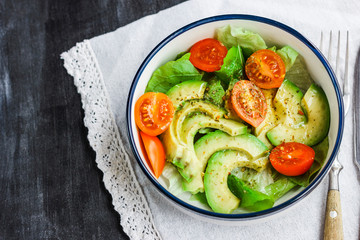 Vegetarian salad with avocado, arugula, cherry tomatoes and herbs.