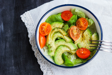Vegetarian salad with avocado, arugula, cherry tomatoes and herbs.