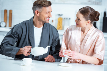 Fototapeta premium selective focus of beautiful adult couple in robes having tea in kitchen