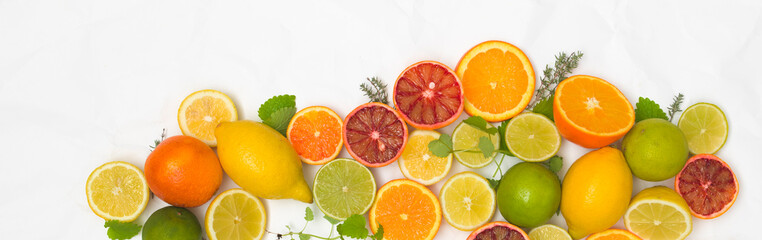 many different fresh citrus fruits on white crumpled paper background