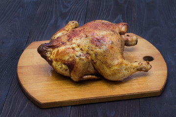 whole roasted chicken in spices on a wooden tray