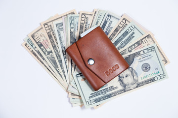 Closeup many american dollar banknotes, closed leather brown small wallet with button. Concept leap, fall, rate, currency exchange, debt, profit, loss, sanctions, appreciation of goods, inflation