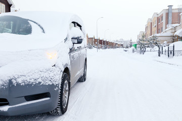 Closeup gray minibus dirty car covered with snow on city background. Front view. Concept snowy weather, fall, bad northern weather conditions, low battery, severe frost, travel big family