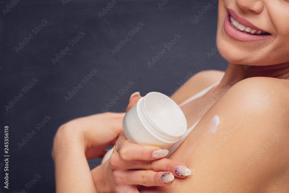 Wall mural Smiling Woman applying body lotion.