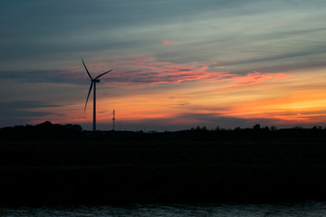 Silhouette of a windturbine and pastel colored clouds at sunset
