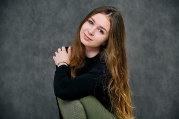 Fototapeta premium Concept Portrait of a pleasant friendly and optimistic happy brunet girl on a gray background with beautiful long hair
