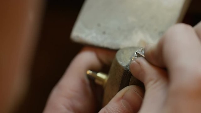 Tilting shot to show a jeweller pushing stones into the indents of a ring