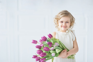Obraz na płótnie Canvas girl holding tulips in hands. Adorable smiling little girl holding flowers for her mom on mother's day.