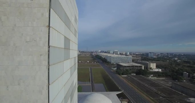 Brasilia aerial sideways tracking shot past the National Congress (Congresso Nacional) with Esplanada dos Ministerios in the background