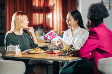 Three young single women reading book about finding husband