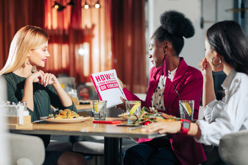 Three single businesswomen reading book about how to find husband