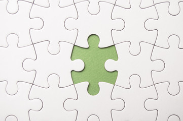 Fototapeta premium the last piece of jigsaw puzzle missing on green background to complete the mission