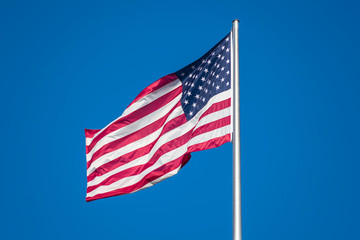 Flag of United States of America waving in wind, against clear sky
