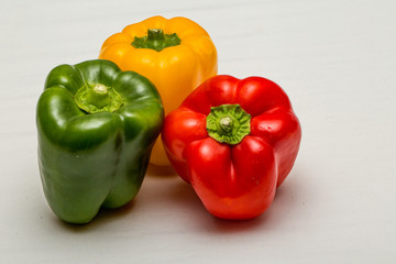 Close up of green pepper, yellow pepper and red pepper isolated against a plain white background
