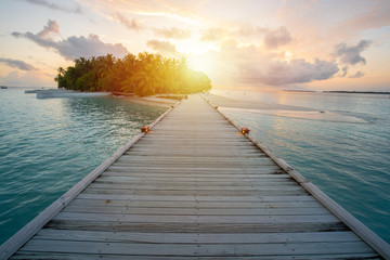 Wooden walkway into resort at Maldive, sun glare from sunset time