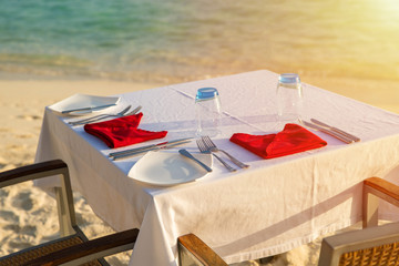 Table outdoor next to sea scenic prepare for special romantic dinner time with sunlight shading..
