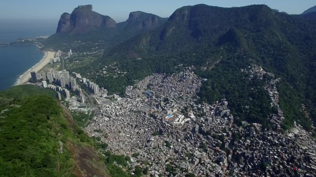 Favela Aerials: High shot above Rocinha favela, Rio de Janeiro, Brazil with wealthy areas in background