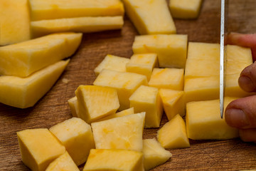 Close up of chef chopping a parsnip on a wooden chopping board