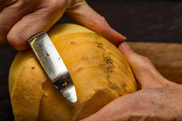 Close up of chef peeling a swede with a vegetable peeler