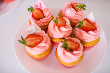 Tasty beautiful pink cake with strawberries, marshmallows, macaroons and huge flower gor the 2 years birthday party