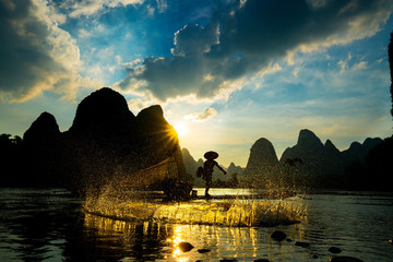 Silhouette of Cormorant fisherman using net on the ancient bamboo boat
