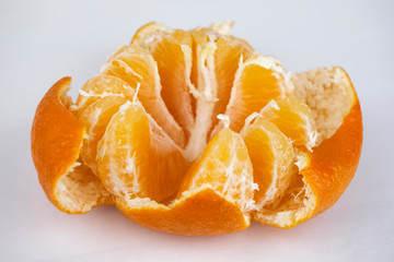 Mandarin disassembled into slices and orange peel located around.