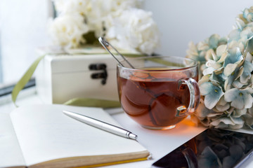 black tea mug, notebook, pen, flowers
