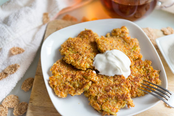 carrot pancakes with sour cream on a plate,