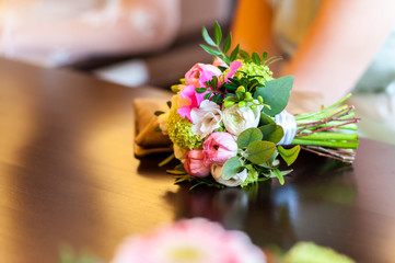 Bride flower bouquet and purse on wooden table
