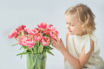 girl holding tulips in hands. Adorable smiling little girl holding flowers for her mom on mother's day.