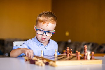 Boy with down syndrome with big glasses playing chess