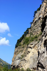 slopes of the Caucasian mountains with green trees against a blue sky with clouds
