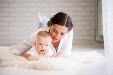 Mother and child in a white room. Mom and baby boy in diaper pla