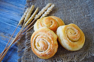Delicious fresh buns and wheat ears on burlap.
