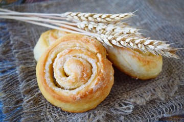 Delicious fresh buns and wheat ears on burlap.