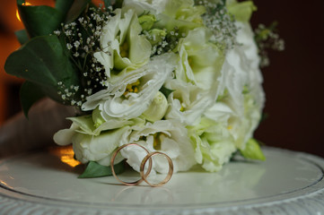 Horizontal shot of wedding rings with a bouquet of the bride. The concept of a wedding day