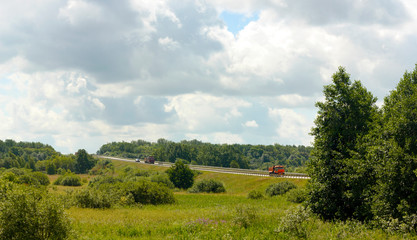Fototapeta na wymiar car trail goes through the fields trucks go in the summer side view