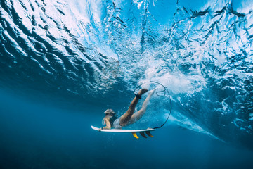 Attractive surfer woman dive underwater under wave.
