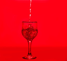 Splashes of water. Glass on a red background. Minimal night party life concept