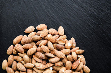 Natural background made in nuts. Black and stone background with almonds.