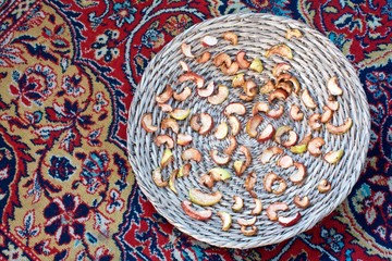 slices of dried apples on a straw plate on the carpet