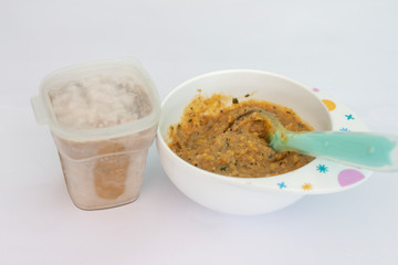 Food grind until fine for babies in bowl with spoon on white background.