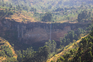 Obraz premium Tall and thin Sipi Falls flowing among rocks in Uganda