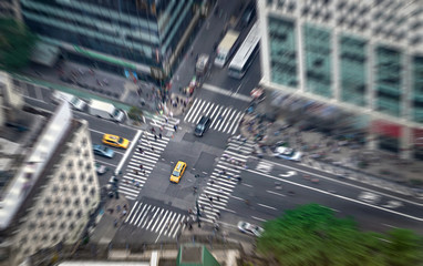 New York city street full of taxis, cars and pedestrians. Yellow cab in focus. Busy NYC Downtown. Crowd of people crossing crosswalks. Traffic jam in NY. Zoom blur effect.