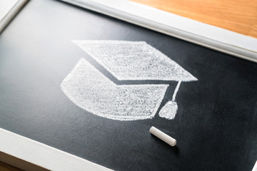 Graduation hat drawn on blackboard with chalk. Applying to college or university concept....