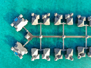 Aerial view of overwater bungalows with thatched roofs in the Bora Bora lagoon in French Polynesia